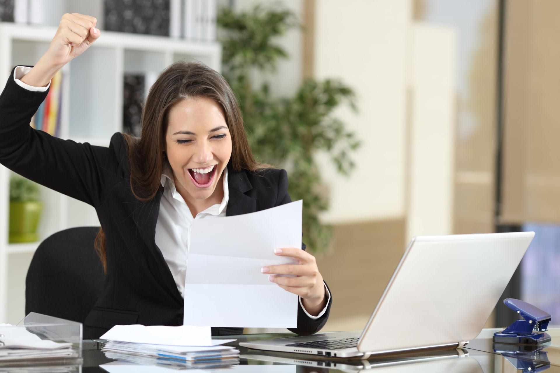 A young woman is in her office feeling excited to secure her finances with a personal line of credit.